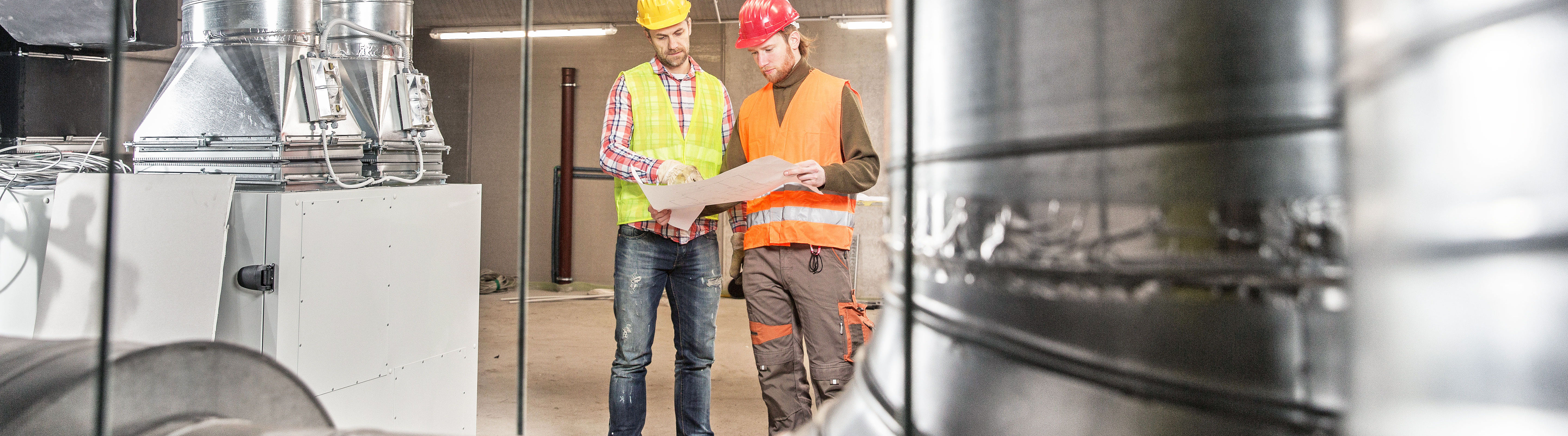 4-ventilations buildings two men with helmet and high visibly vest reading plan of a ventilation system