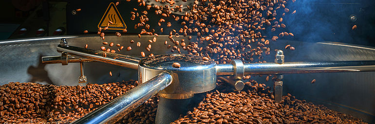 detail view coffee falling into a machine for drying and roasting