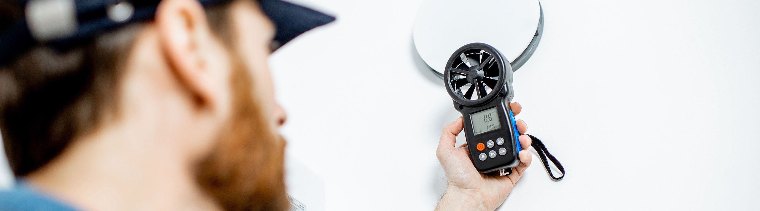 man with basecap and air flow meter anemometer