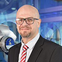 Marius du Plessis mit Brille, Jacket & rot weißer Krawatte