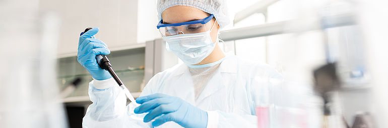 Lab technician in clean room analyzing