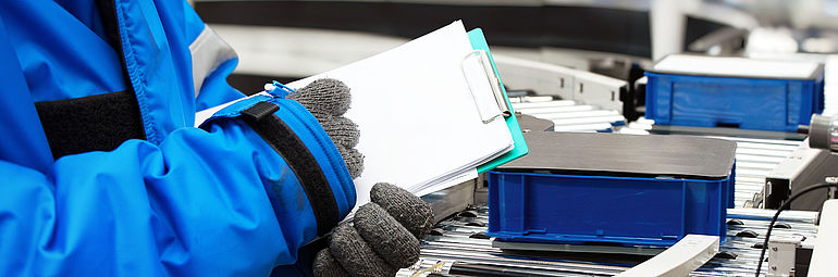 person with blue jacket documents blue boxes on a roll track