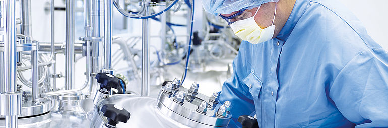 Chemical lab technician with blue protective clothing in clean room