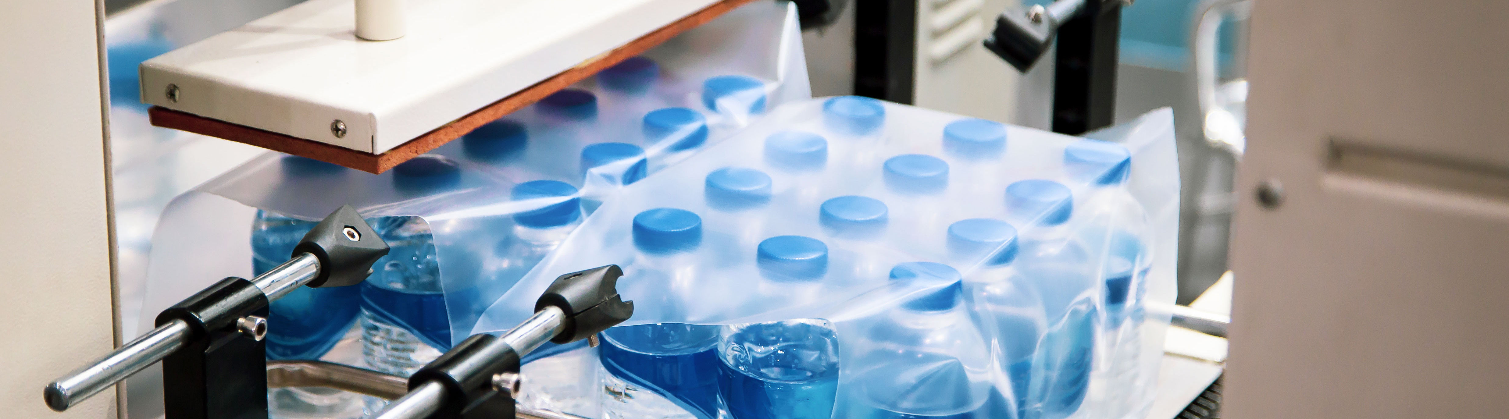 Machine packs pallet with blue plastic bottles