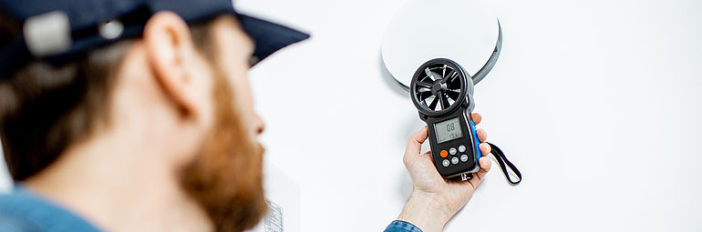man with basecap and air flow meter anemometer