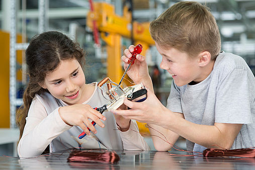 Interessante Einblicke beim Maus Türöffnertag Zwei Kinder schrauben an einer kleinen Kupferspule