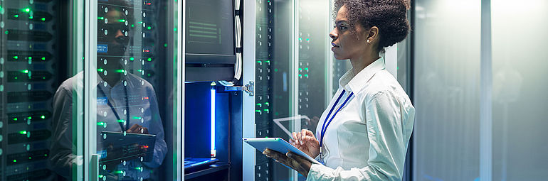 Woman with tablet PC standing in front of server
