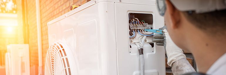 person checking wire in heat pump