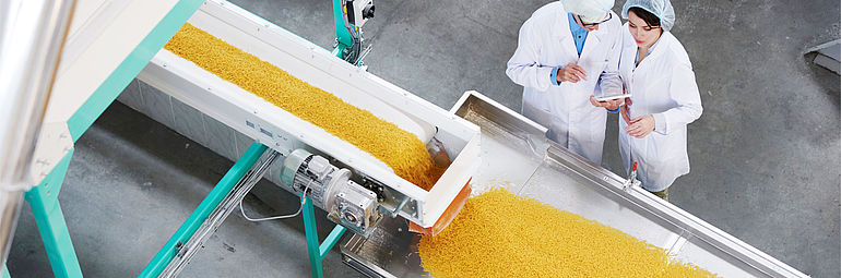 two people with tablet PC next to production machine for drying pasta