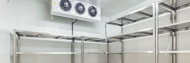Cooling system in cold room above empty steel shelves