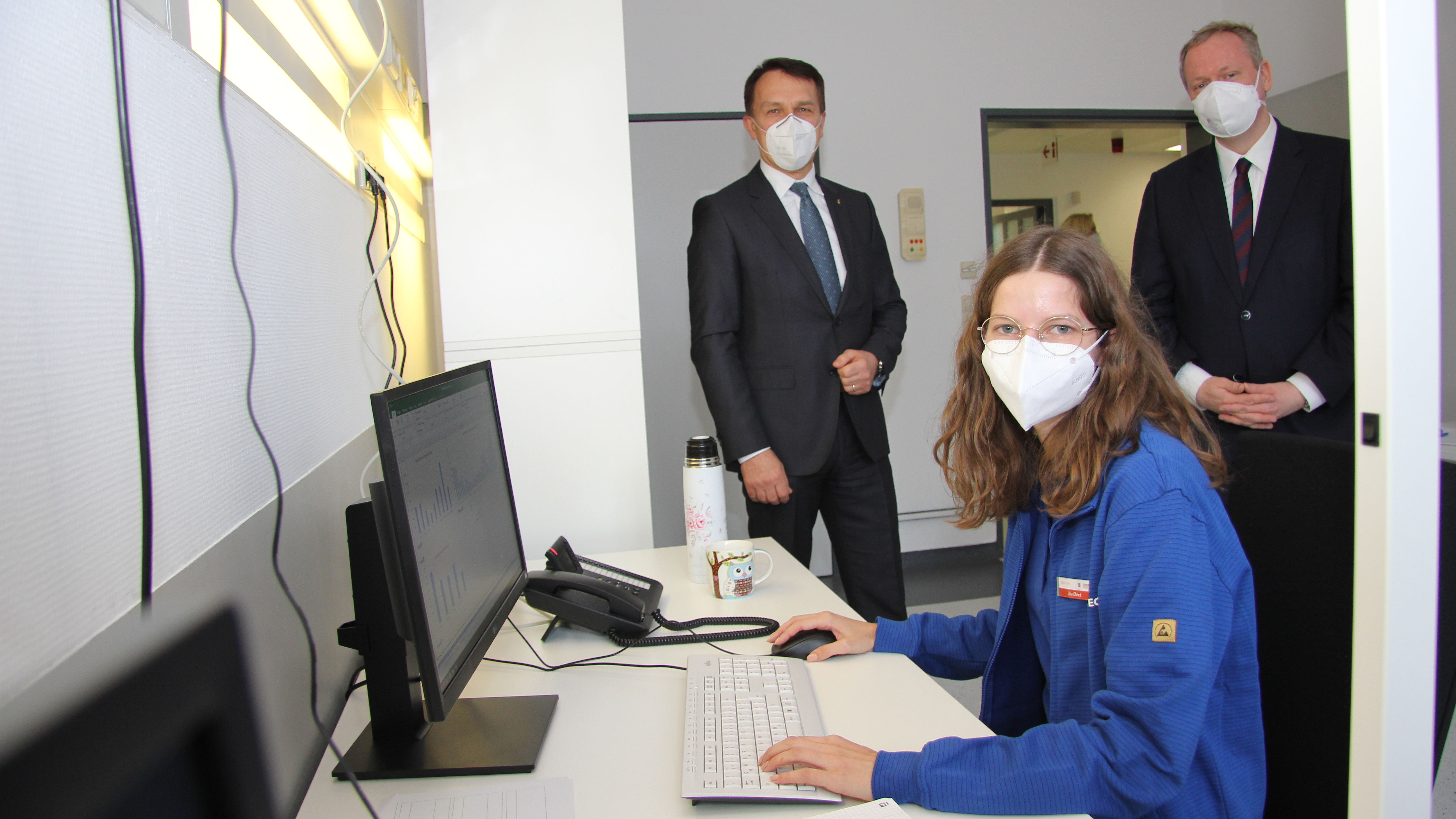 Ziehl-Abegg-Mitarbeiterin Lisa Ehret arbeitet an der Corona-Hotline im Gesundheitsamt; hinter ihr sind Vorstandsvorsitzender Peter Fenkl (links) und Landrat Dr. Matthias Neth.