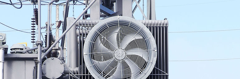 Big axial fan with protective grill is cooling a power generation plant