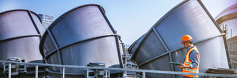 Man in front of cooling towers with safety clothing and documents