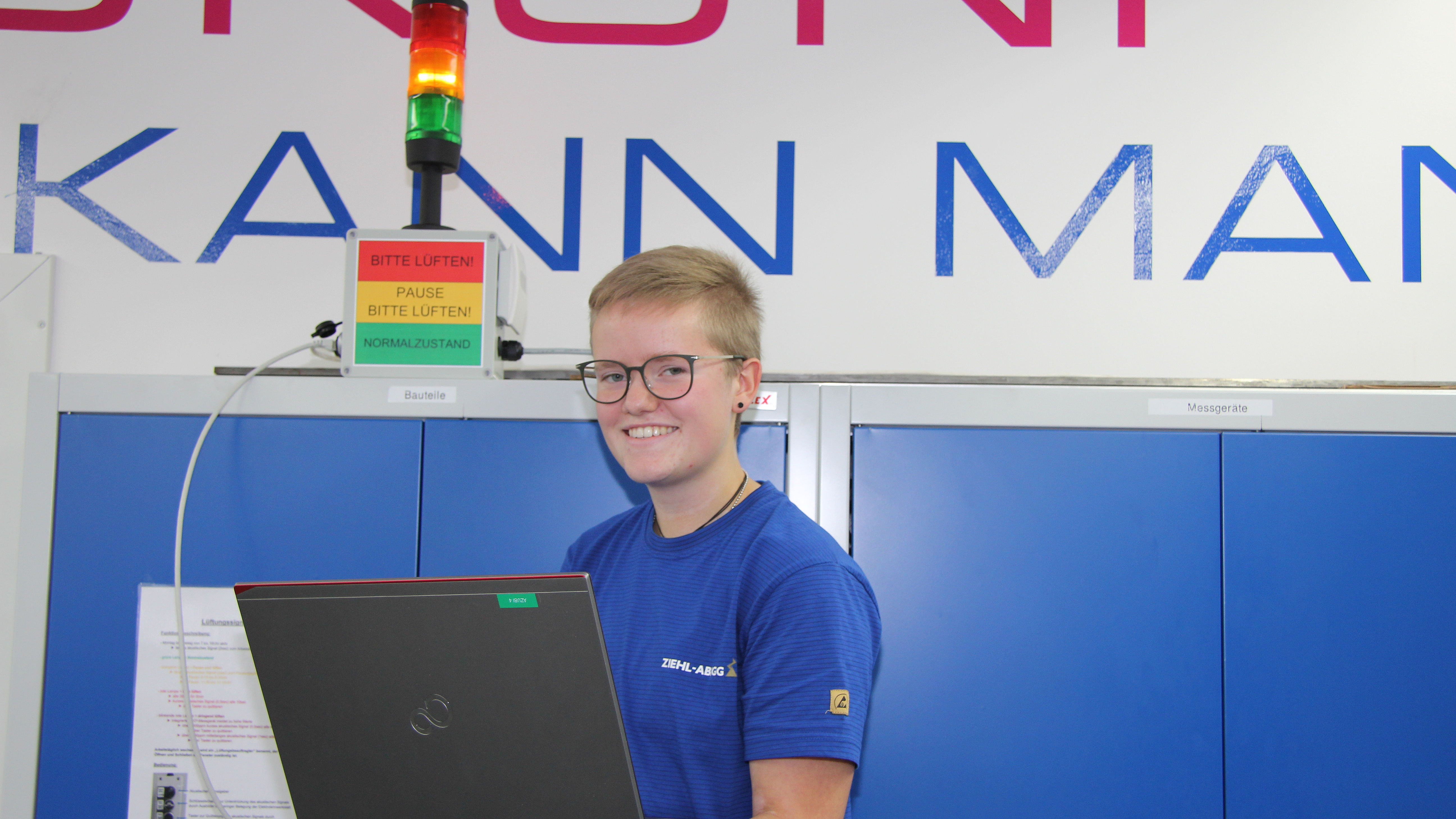 Lena Uhlig programmiert mit dem Laptop die Steuerung der Warnanlage; diese weist Azubis und duale Studenten im Schulungsraum bei Ziehl-Abegg auf die Qualität der Raumluft hin.
