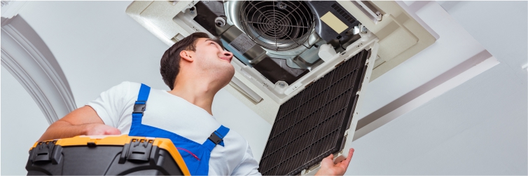 young man opening a ventilation system at the ceiling