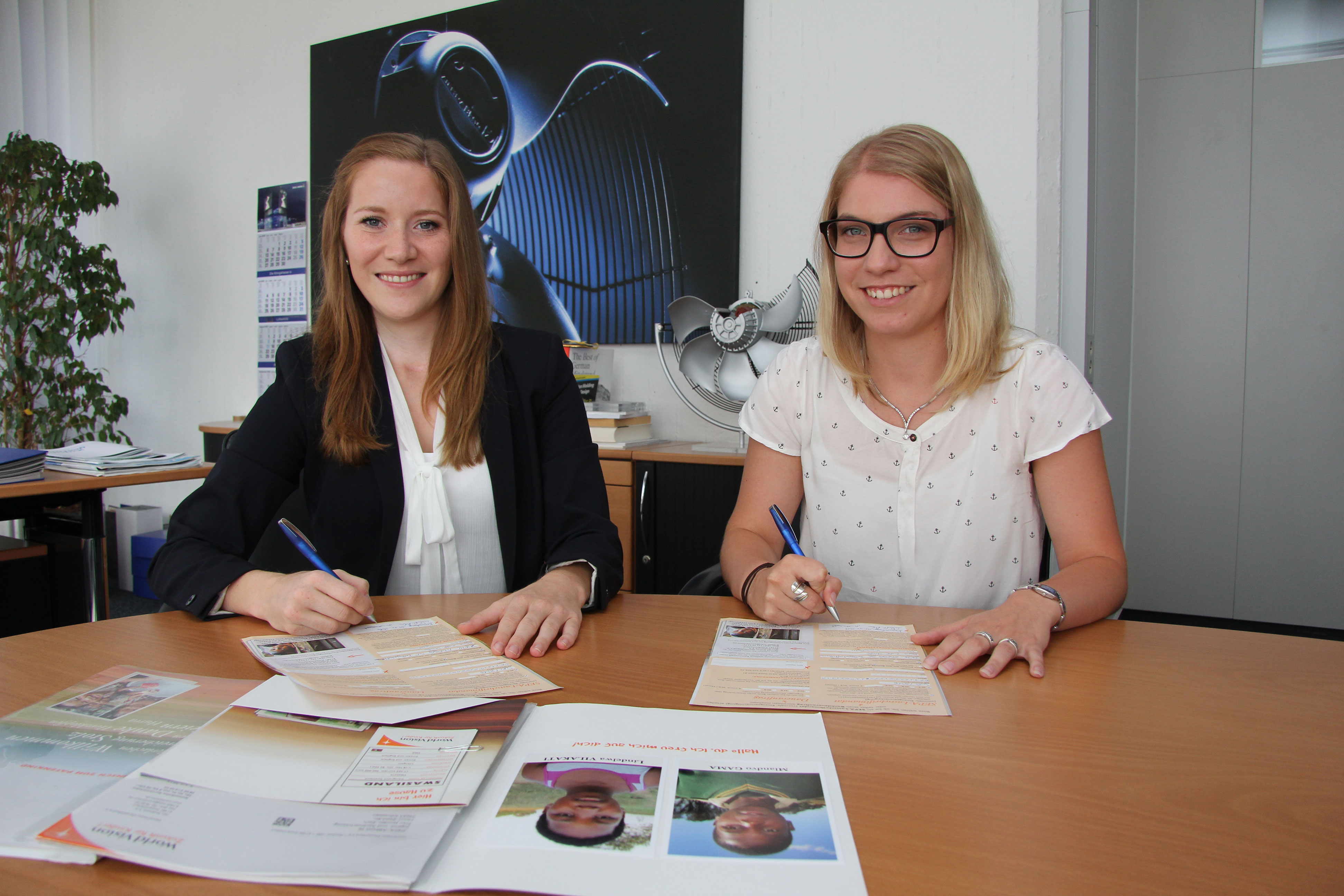 The Ziehl-Abegg apprentices Jennifer Zürn (left) and Marlen Geißler sign the sponsorship for two children in Swaziland.