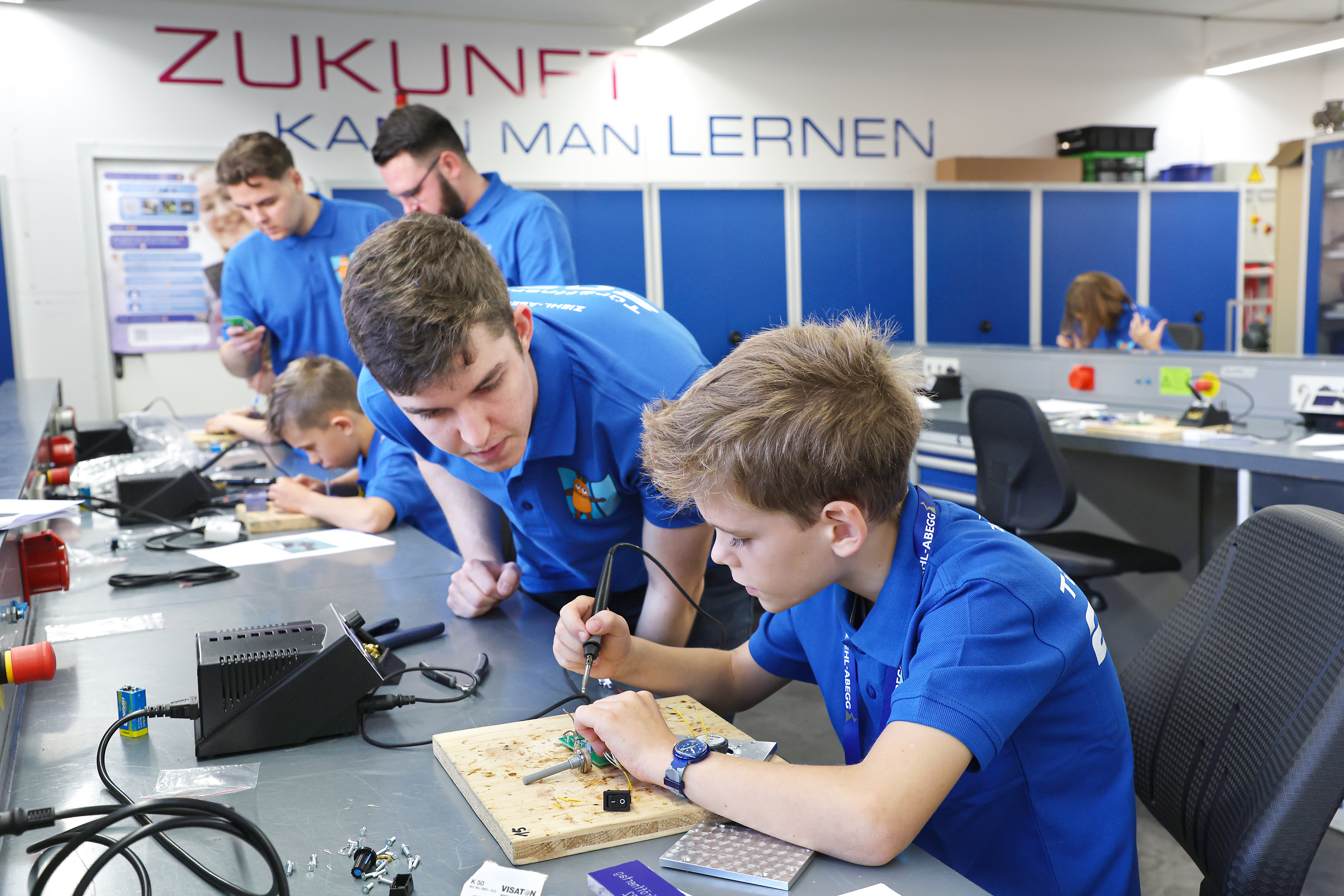 Kinder in blauen T-shirts bauen einen Lautsprecher