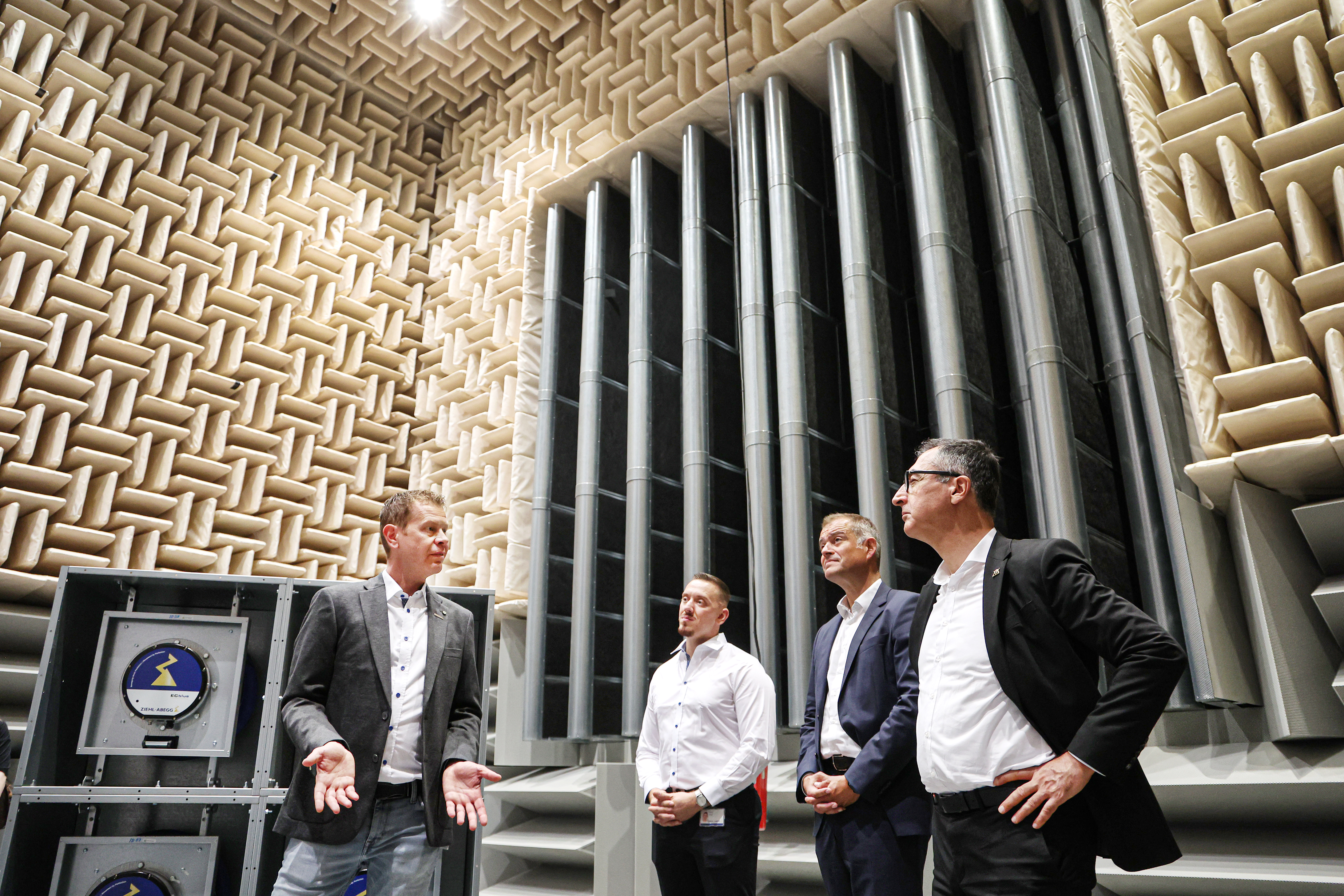 Achim Kärcher (left), Head of Laboratory, explains the design and operation of the world's largest combined fan test chamber. Listening are (from right) Baden-Württemberg's Minister-President Cem Özdemir, Chief Executive Officer Joachim Ley and Works Council Chairman Rinor Imeri